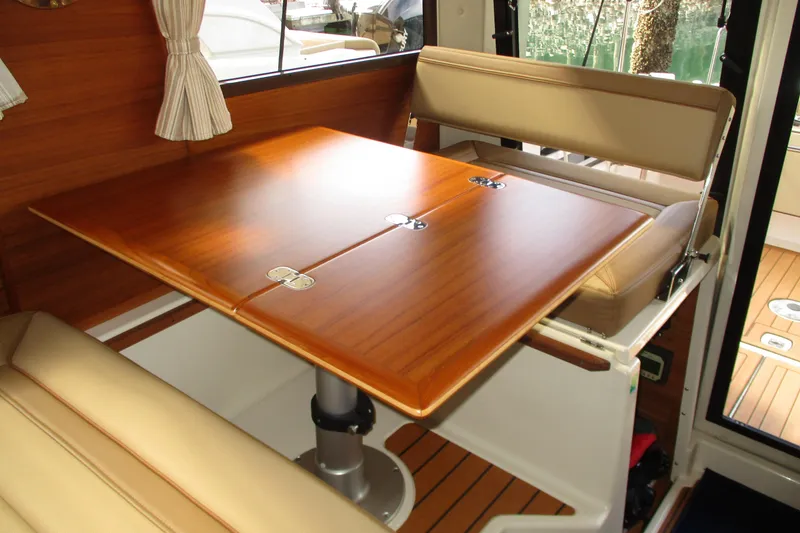 Slide: The Image of Interior of 2022 Ranger Tugs R-27 with wooden table and beige seating. - 50