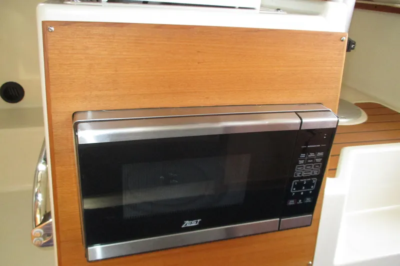 Slide: The Image of Microwave in 2022 Ranger Tugs R-27 boat interior, featuring wood paneling. - 57