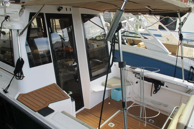 Slide: The Image of 2022 Ranger Tugs R-27 boat with teak deck and canopy, docked at marina. - 71