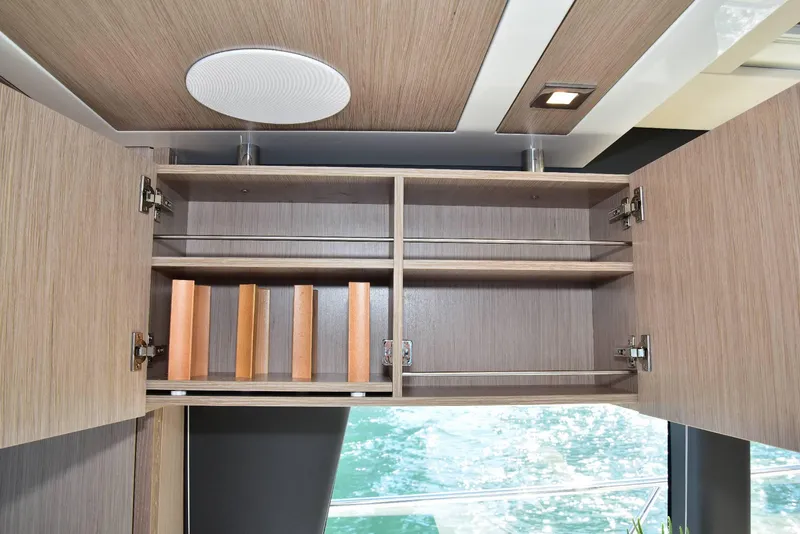 Slide: The Image of 2022 Sealine C430 yacht interior cabinet with open doors, showcasing wooden shelves and books. - 21