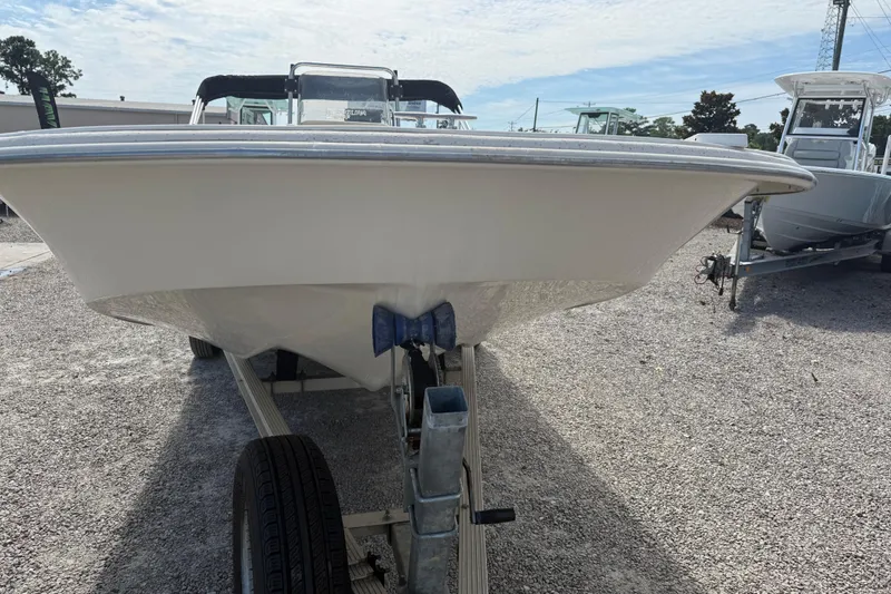Slide: The Image of 2016 Carolina Skiff 218 DLV boat on trailer, parked on gravel lot under blue sky. - 11