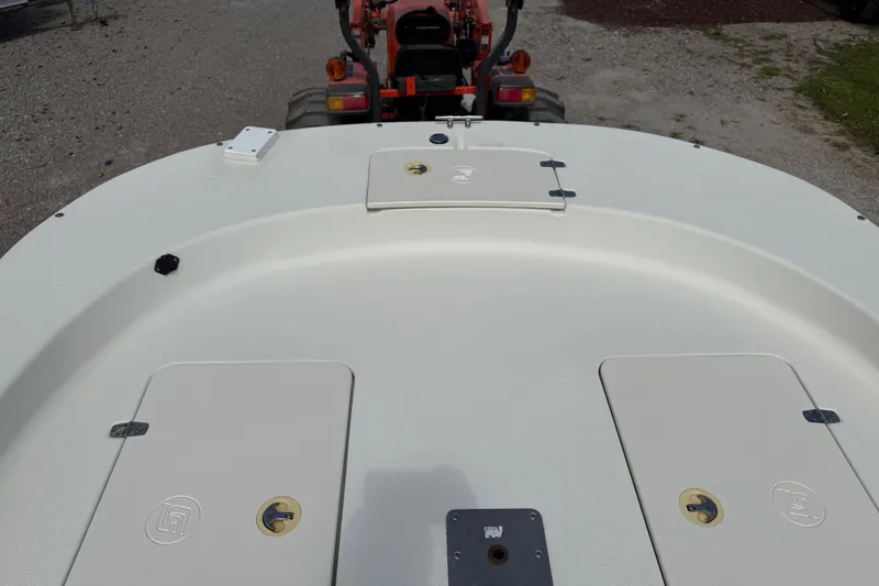 Slide: The Image of 2016 Carolina Skiff 218 DLV boat deck with storage compartments and tractor in background. - 14