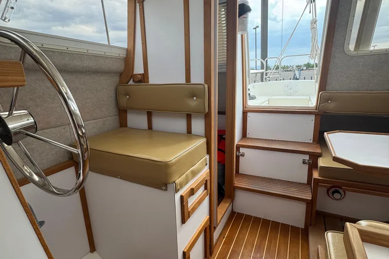 Slide: The Image of 2022 Com-Pac CP 23 Pilothouse interior with helm, seating, and wooden accents. - 12