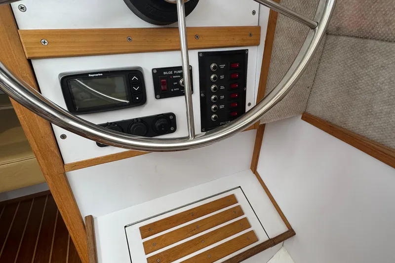 Slide: The Image of 2022 Com-Pac CP 23 Pilothouse helm with steering wheel, control panel, and navigation equipment. - 15