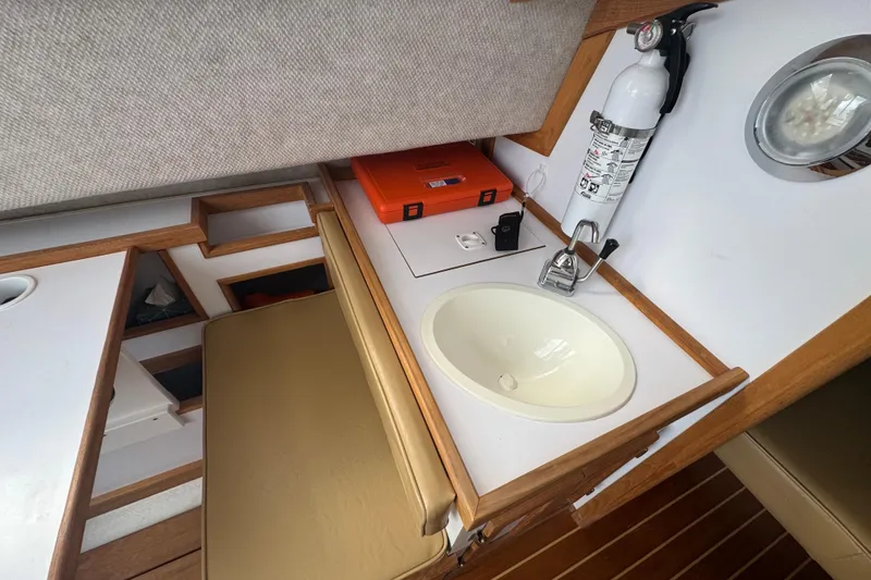 Slide: The Image of 2022 Com-Pac CP 23 Pilothouse interior with sink, fire extinguisher, and wooden accents. - 17