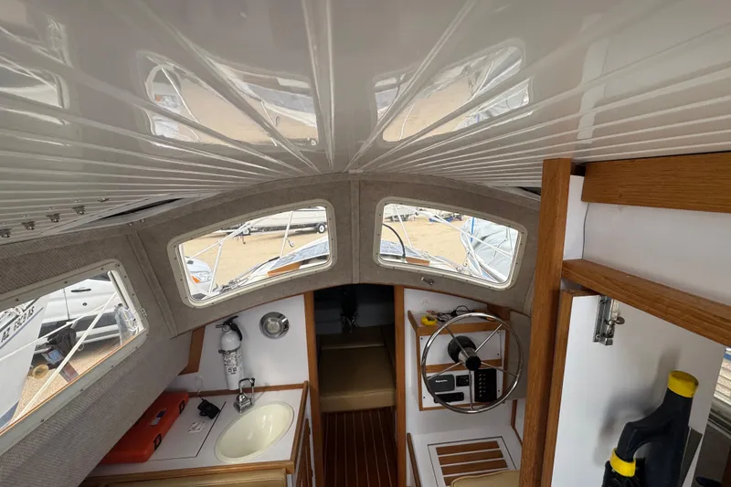 Slide: The Image of Interior of 2022 Com-Pac CP 23 Pilothouse, featuring helm, sink, and wooden accents. - 18