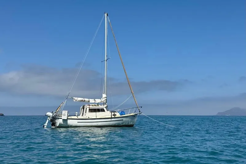 Slide: The Image of 2022 Com-Pac CP 23 Pilothouse sailboat anchored on calm blue sea. - 2