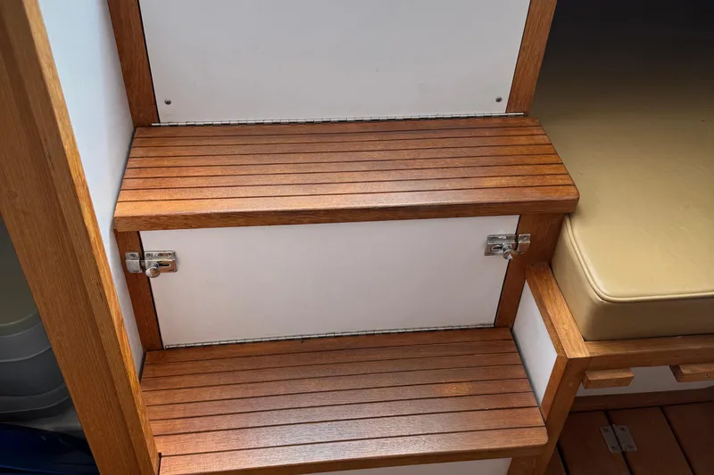 Slide: The Image of 2022 Com-Pac CP 23 Pilothouse interior with wooden steps and storage compartments. - 24