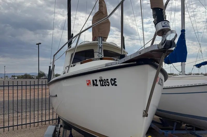 Slide: The Image of 2022 Com-Pac CP 23 Pilothouse sailboat on trailer, parked near a fence. - 4