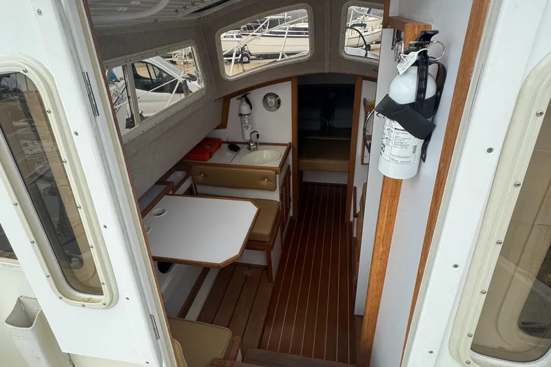 Slide: The Image of Interior of 2022 Com-Pac CP 23 Pilothouse, featuring seating and wooden flooring. - 8