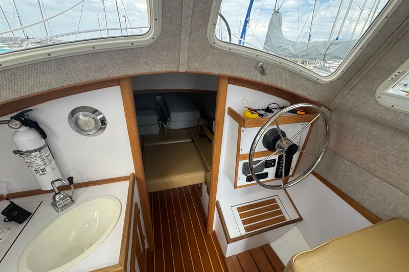 Slide: The Image of Interior of 2022 Com-Pac CP 23 Pilothouse with helm, sink, and cabin view. - 9