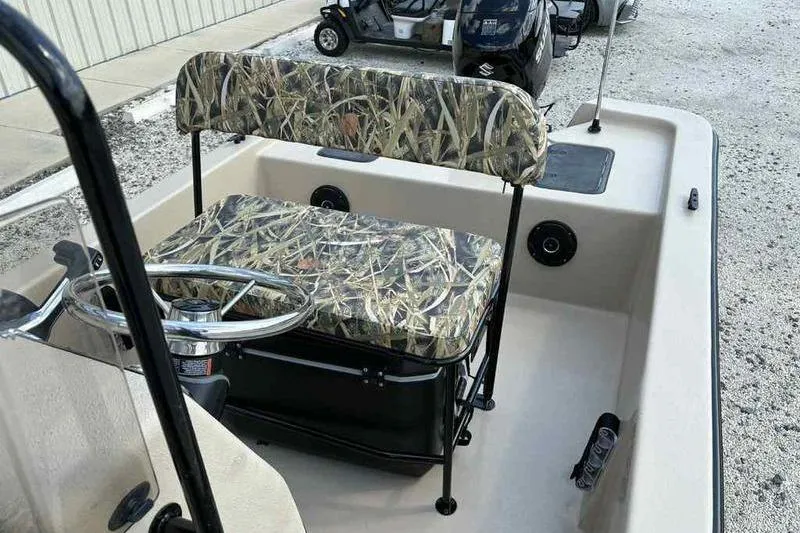 Slide: The Image of 2026 Carolina Skiff E18 JVX TH boat interior with camo seating and steering wheel. - 10