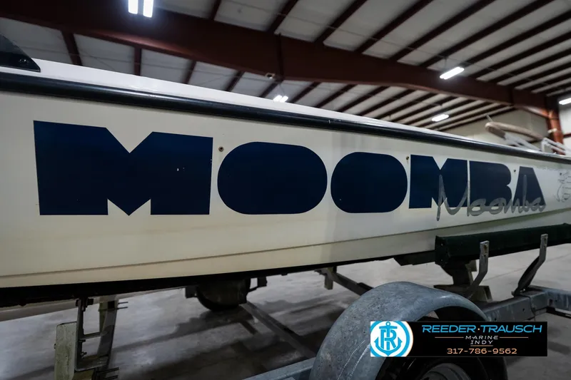Slide: The Image of 1997 Moomba Boomerang boat on trailer in showroom, featuring front view and hitch details. - 43