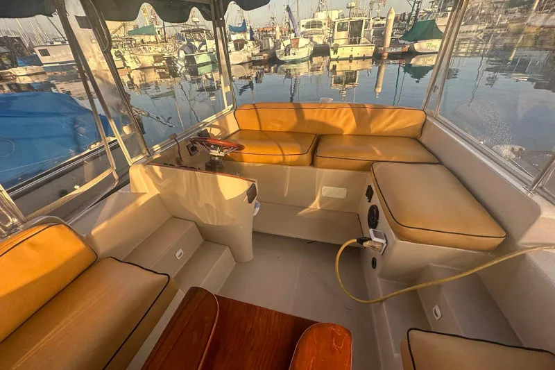 Slide: The Image of Interior of a 2007 Duffy 22 Electric boat with tan seating and marina view. - 13