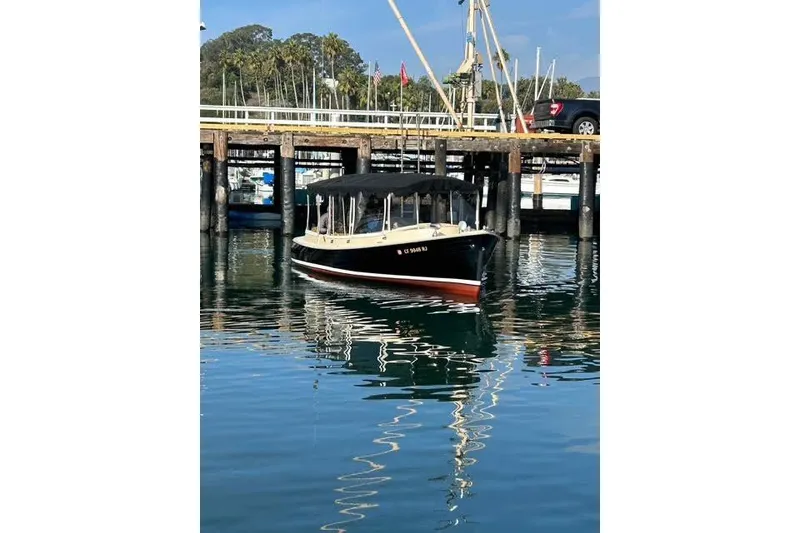 Slide: The Image of 2007 Duffy 22 Cuddy boat docked at a marina, reflecting on calm water. - 2