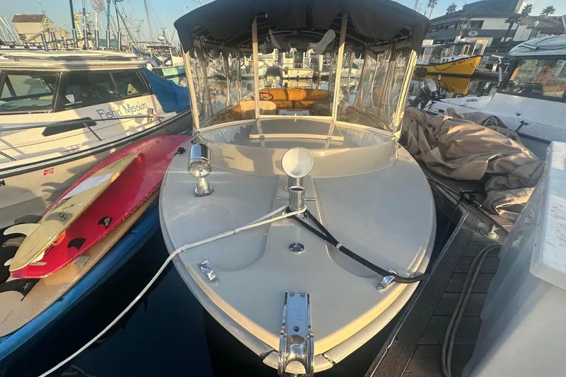 Slide: The Image of 2007 Duffy 22 Electric boat docked, surrounded by other boats and surfboards. - 7