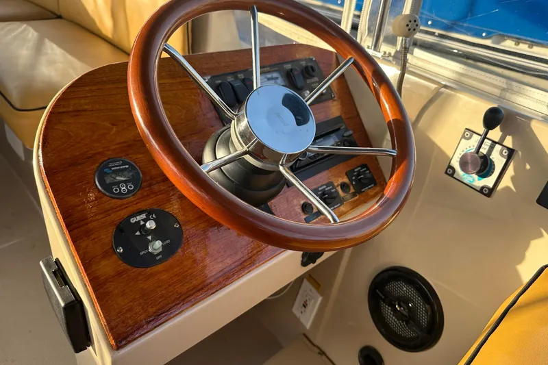 Slide: The Image of Steering wheel and controls of a 2007 Duffy 22 Electric boat, featuring wood accents. - 9