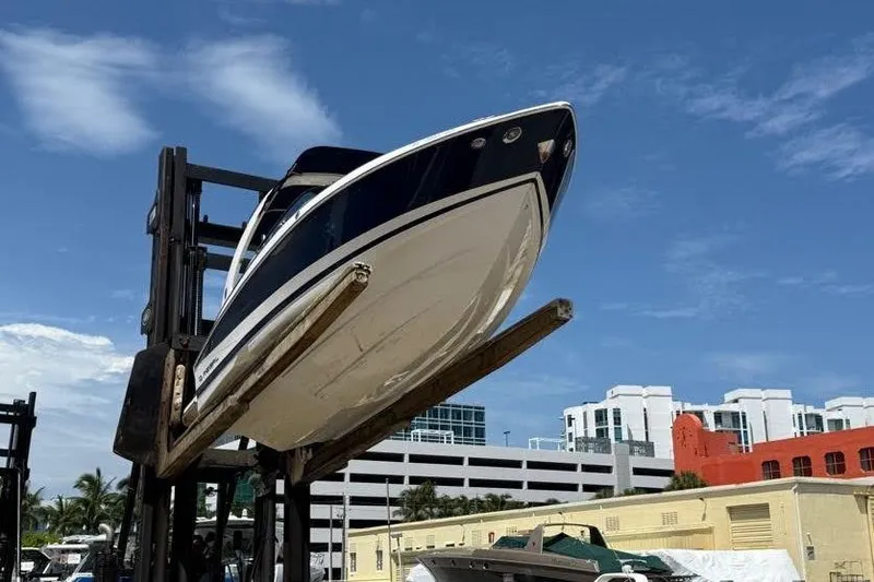 Slide: The Image of 2014 Regal 2500 Bowrider boat lifted by forklift against blue sky. - 2