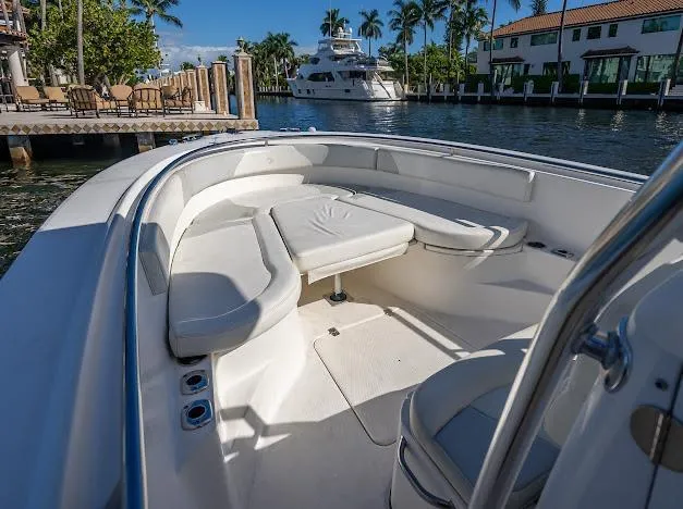 Slide: The Image of 2010 Edgewater 318CC boat interior with seating, docked near waterfront homes and palm trees. - 19