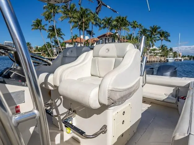 Slide: The Image of 2010 Edgewater 318CC boat interior with white seating, palm trees, and waterfront view. - 31