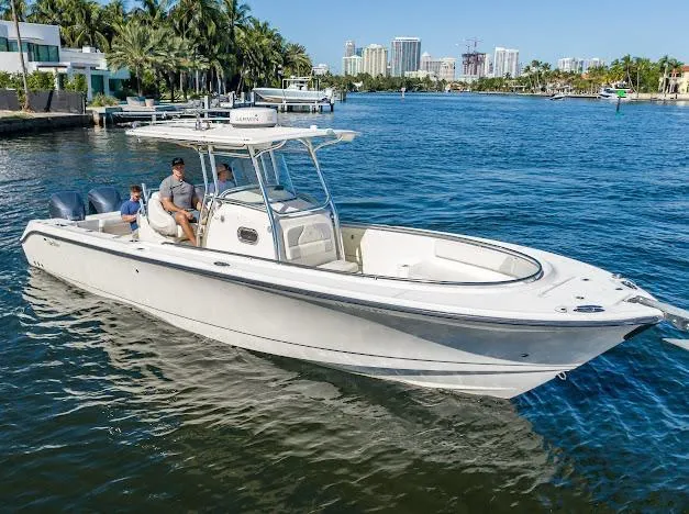 Slide: The Image of 2010 Edgewater 318CC boat cruising on a sunny waterfront with city skyline. - 5