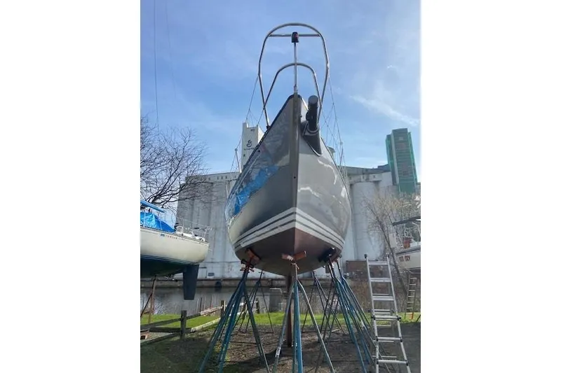 Slide: The Image of 1990 Tartan Thomas 35 sailboat on stands, urban backdrop, clear sky. - 12