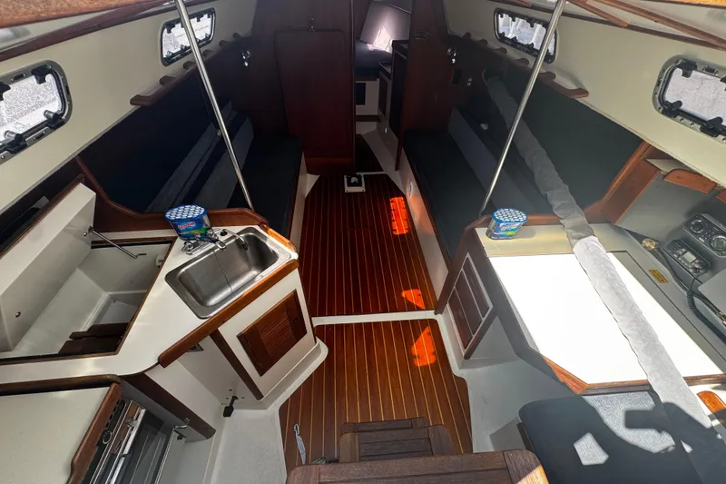 Slide: The Image of Interior of 1990 Tartan Thomas 35 sailboat with wood flooring and compact kitchen area. - 13