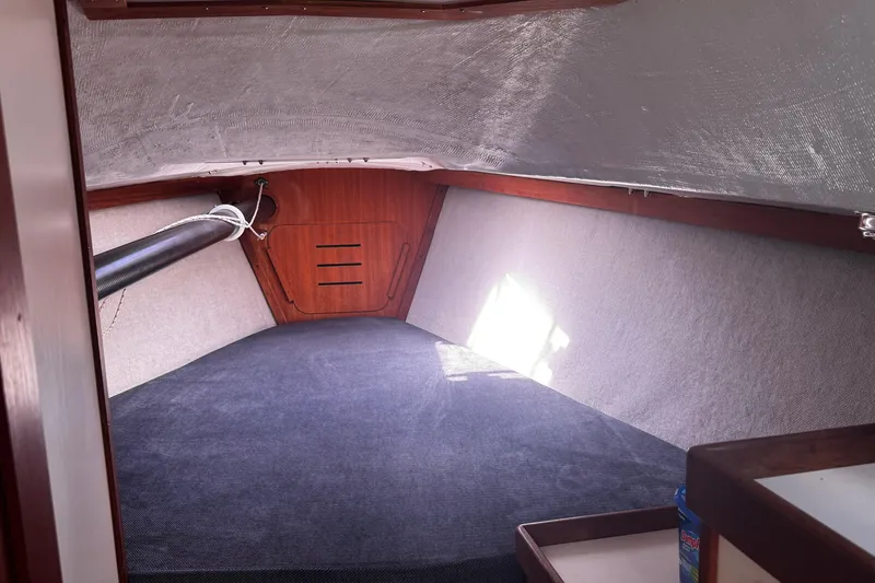 Slide: The Image of Interior cabin of 1990 Tartan Thomas 35 sailboat, featuring wood paneling and carpeted flooring. - 21