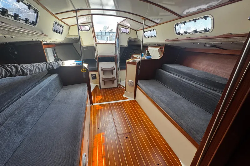 Slide: The Image of Interior of a 1990 Tartan Thomas 35 sailboat with wooden flooring and cushioned seating. - 23
