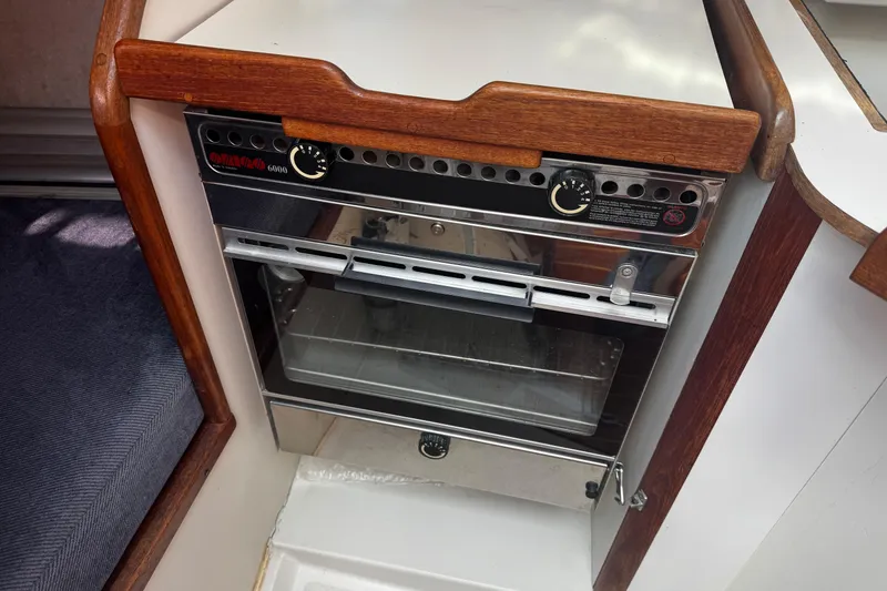 Slide: The Image of 1990 Tartan Thomas 35 boat interior with a compact oven and wooden trim. - 27