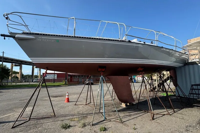 Slide: The Image of 1990 Tartan Thomas 35 sailboat on stands in a boatyard under clear blue sky. - 36