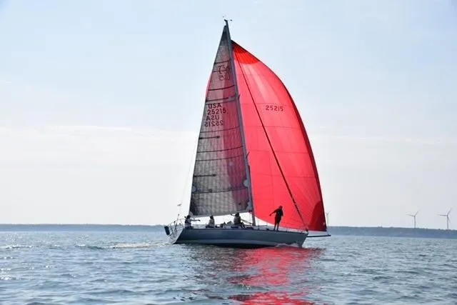 Slide: The Image of Sailboat Tartan Thomas 35, 1990 model, with red sail on calm water. - 8