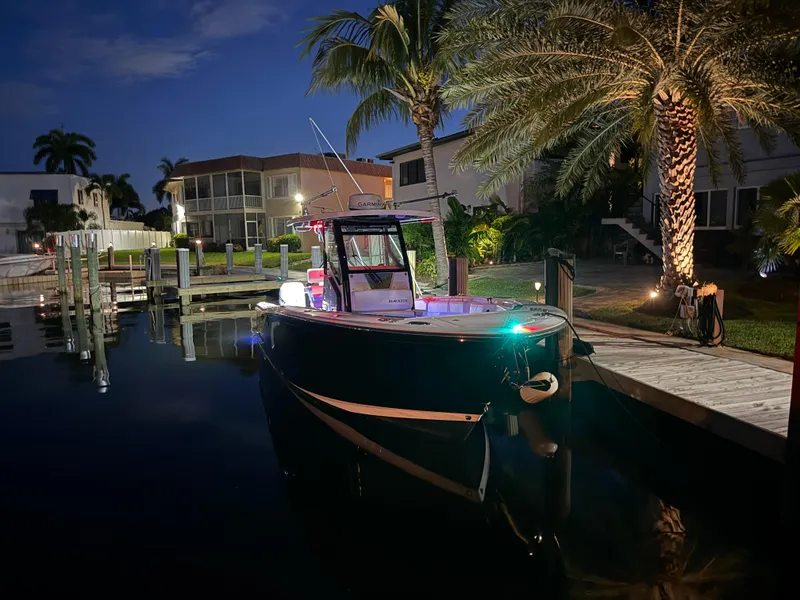 Slide: The Image of 2019 Blackfin 272 CC boat docked at night, surrounded by palm trees and waterfront homes. - 3