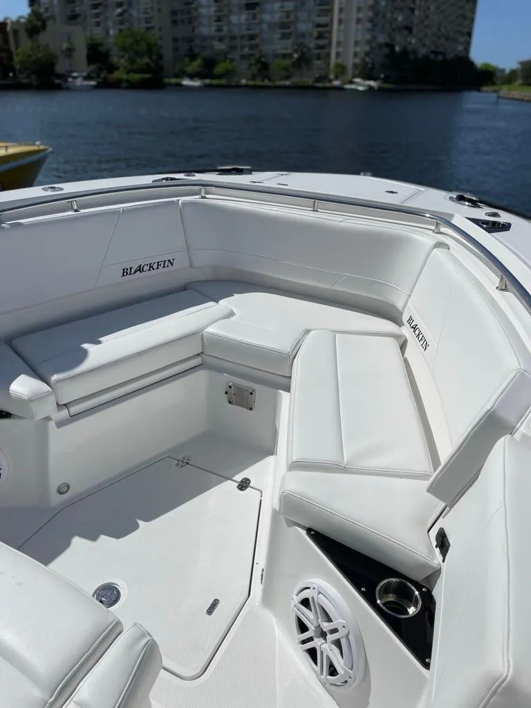 Slide: The Image of 2019 Blackfin 272 CC boat with white seating, docked by waterfront buildings. - 40