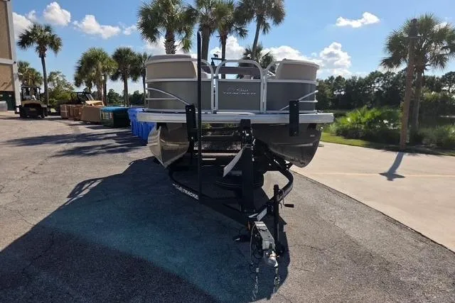 Slide: The Image of 2017 Sun Tracker Party Barge 20 DLX on trailer, parked near palm trees. - 2