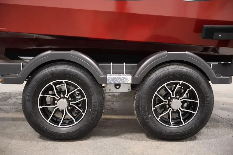 Slide: The Image of 2026 Lowe Fishing Machine 1875 trailer wheels, black rims, and red boat hull. - 45