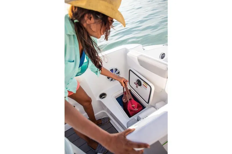Slide: The Image of Woman accessing storage on 2020 Tahoe 2150 CC boat, wearing a hat and casual attire. - 18