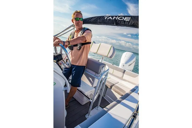 Slide: The Image of Man steering 2020 Tahoe 2150 CC boat on open water, under clear blue sky. - 20