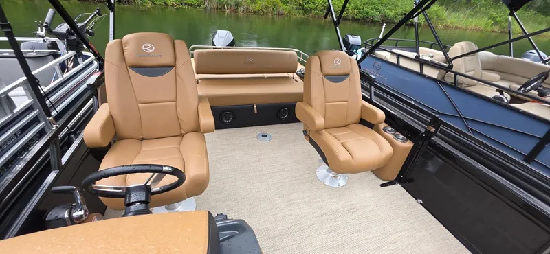 Slide: The Image of 2024 Regency 230 LE3 Sport boat interior with tan seating and steering wheel. - 11