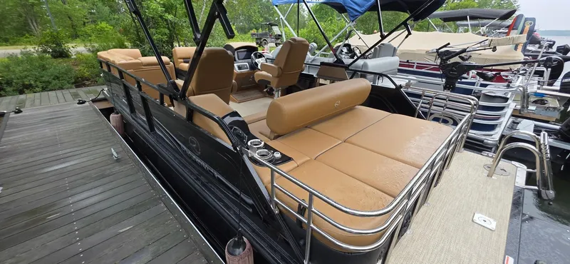 Slide: The Image of 2024 Regency 230 LE3 Sport pontoon boat with tan seating, docked on a wooden pier. - 16
