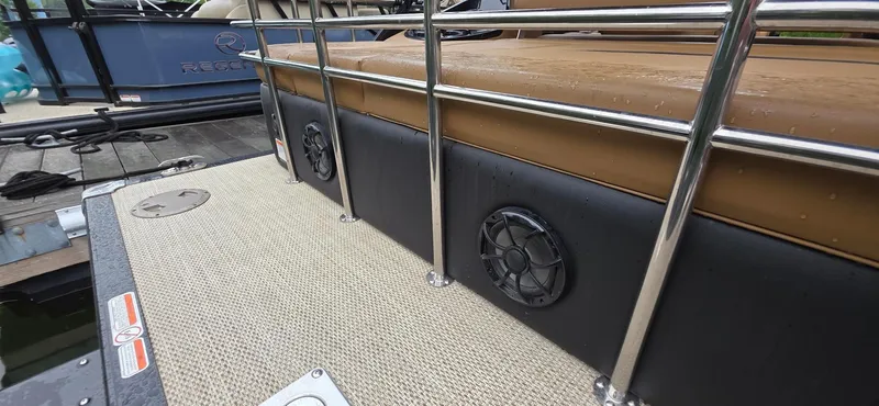 Slide: The Image of 2024 Regency 230 LE3 Sport boat deck with speakers and railing, docked at marina. - 7