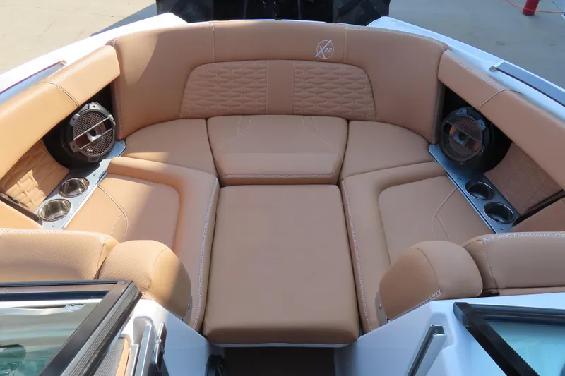 Slide: The Image of Luxurious tan seating in 2019 MasterCraft X22 boat interior with cup holders and speakers. - 13