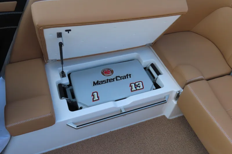 Slide: The Image of 2019 MasterCraft X22 boat storage compartment with tan seating and branded cooler. - 17
