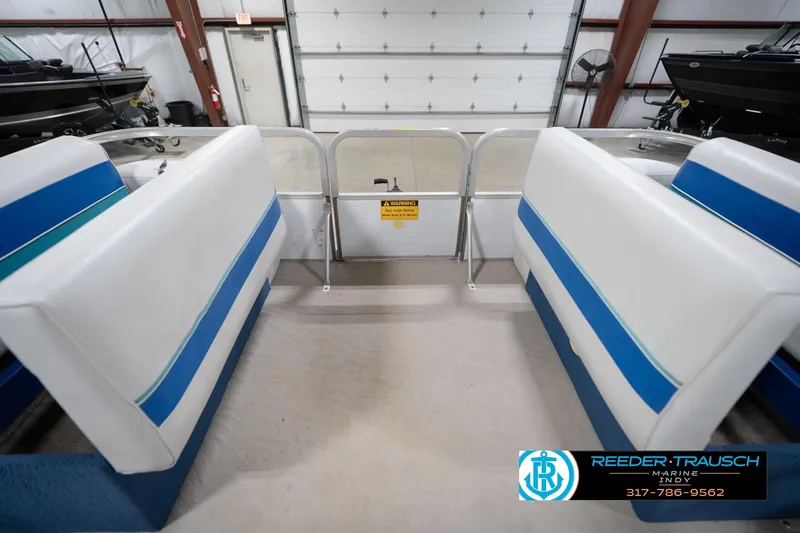 Slide: The Image of 1996 Godfrey Sweetwater 180 EX pontoon boat interior with blue and white seating in a showroom. - 21