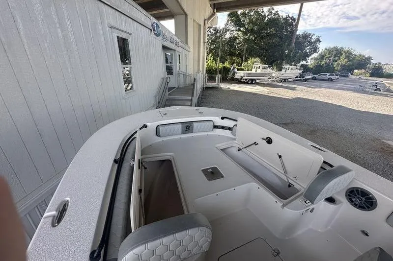 Slide: The Image of 2026 Carolina Skiff 24 Ultra Elite boat interior at a dealership, showcasing seating and storage. - 13