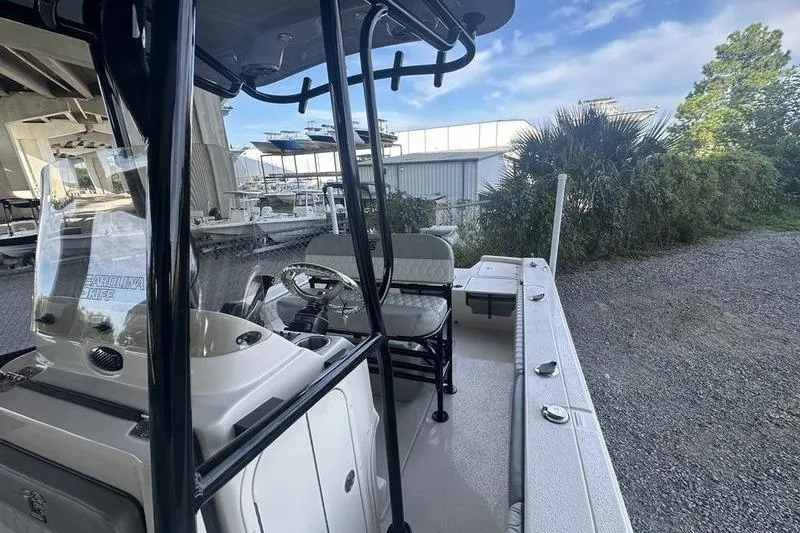 Slide: The Image of 2026 Carolina Skiff 24 Ultra Elite boat with console and seating, parked outdoors. - 15