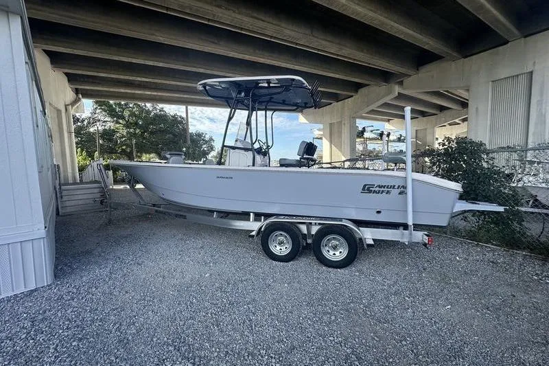 Slide: The Image of 2026 Carolina Skiff 24 Ultra Elite boat on trailer under bridge. - 2