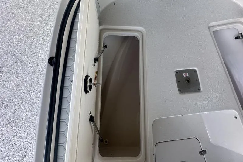 Slide: The Image of 2026 Carolina Skiff 24 Ultra Elite boat storage compartment, open hatch view. - 24
