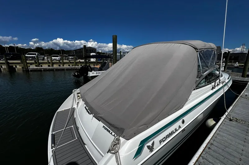 Slide: The Image of 1997 Formula 330 Sun Sport boat docked with cover, under clear blue sky. - 2
