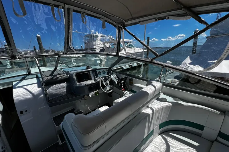 Slide: The Image of 1997 Formula 330 Sun Sport boat interior with helm, docked under clear blue sky. - 3